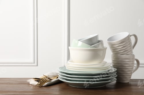 Preview: Beautiful ceramic dishware, cups and cutlery on wooden table, space for text