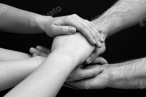 Preview: Group of people stacking their hands together, closeup. Black-and-white toning