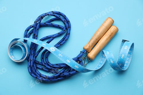 Preview: Measuring tape and jumping rope on light blue background, flat lay