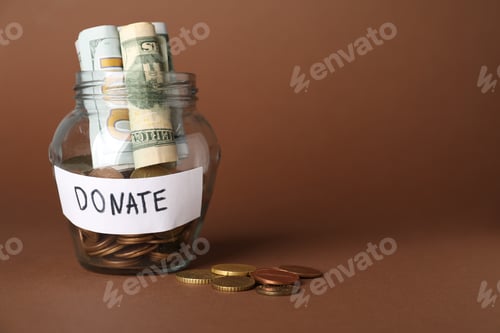 Vista previa: Donation jar with dollar banknotes and coins on brown background, closeup. Space for text