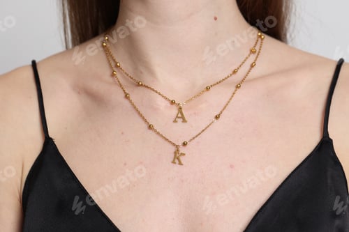 Preview: Woman wearing stylish golden necklace on light background, closeup