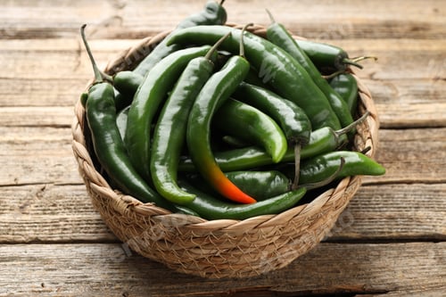 Preview: Fresh chili peppers in wicker basket on wooden table, closeup
