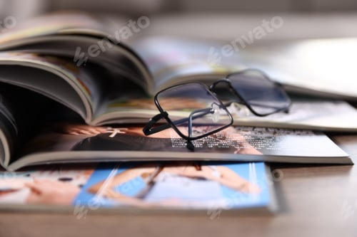Preview: Many lifestyle magazines and glasses on wooden table, closeup