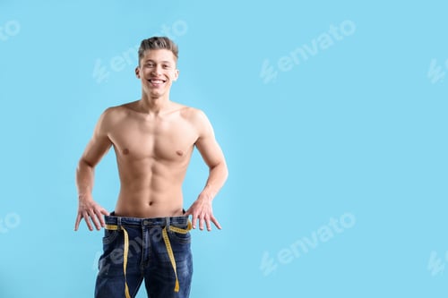Preview: Athletic man wearing big jeans with measuring tape on light blue background, space for text