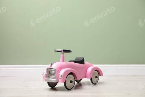 Preview: Pink toy car near light green wall indoors