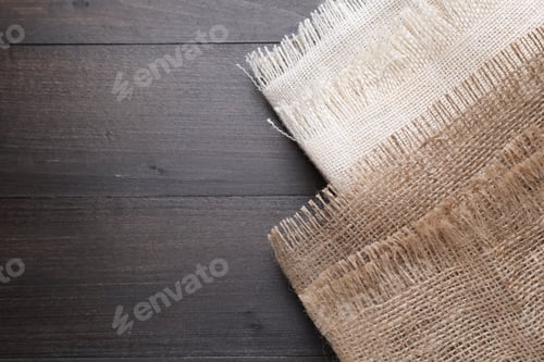 Preview: Folded natural burlap fabrics on wooden table, top view. Space for text
