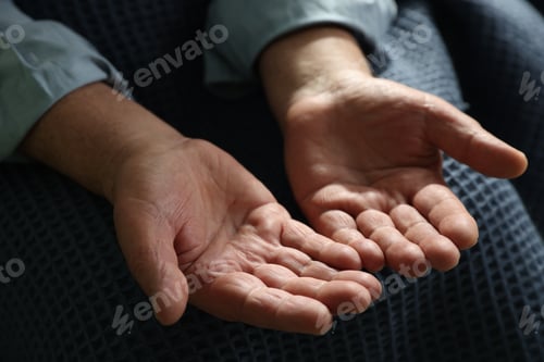 Preview: Elderly man covering with blue blanket holding something, closeup