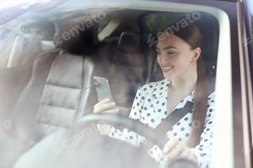 Preview: Woman with smartphone driving modern car, view through windshield