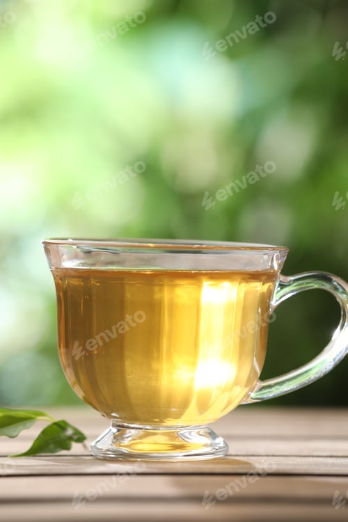 Preview: Aromatic tea in glass cup on wooden table outdoors, closeup
