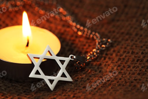 Preview: Holocaust Remembrance Day. Pendant in shape of Star of David and burning candle on burlap cloth, clo
