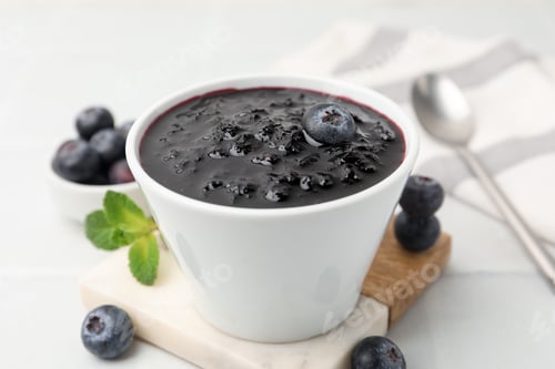 Preview: Sweet jam in bowl, blueberries and mint on white table, closeup