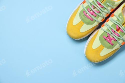 Preview: Pair of stylish sneakers on light blue background, flat lay. Space for text