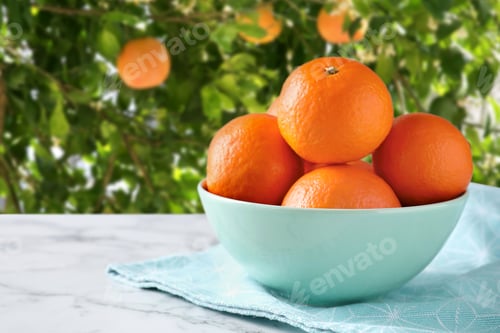 Preview: Fresh juicy tangerines in bowl on wooden table near tree outdoors