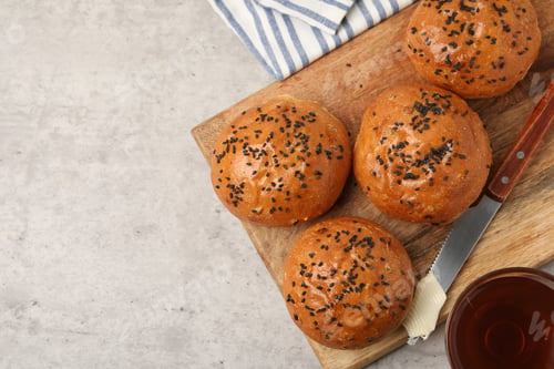 Preview: Sesame seed buns served with butter and tea on grey table, top view. Space for text