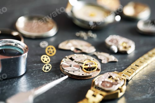 Preview: Mechanism of vintage wrist watch and gears on black table, closeup