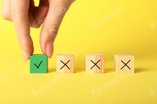 Preview: Woman putting wooden cube with checkmark next to others with cross marks on yellow background, close