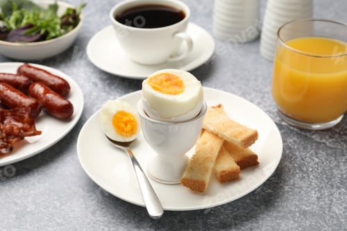 Preview: Tasty breakfast with hard boiled egg served on grey table, closeup