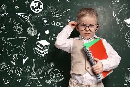 Preview: Cute little child in glasses near green chalkboard with formulas and drawings