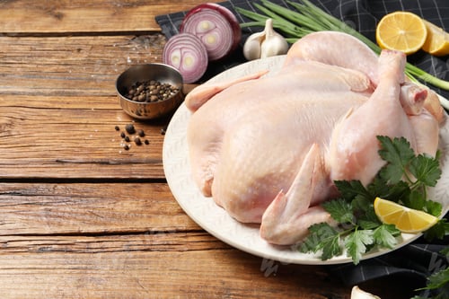 Preview: Fresh raw chicken with different products on wooden table, space for text