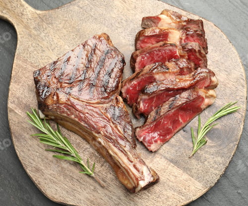 Preview: Pieces of tasty beef steak with rosemary on black table, top view