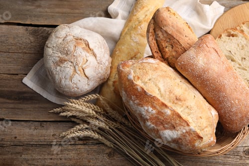Preview: Different types of bread and wheat spikes on wooden table, flat lay