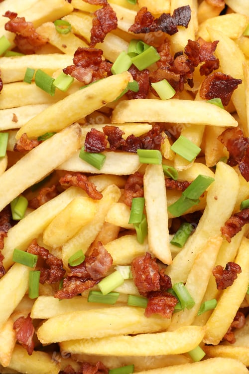 Preview: Delicious French fries with bacon and green onion as background, top view