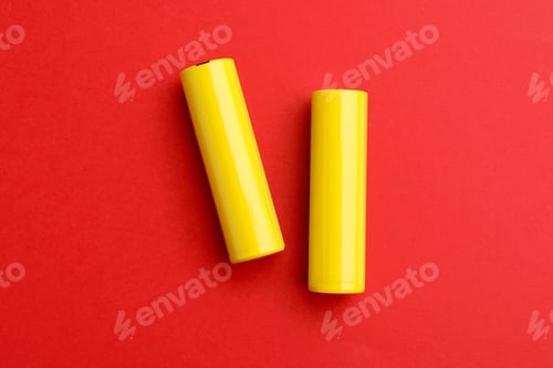 Preview: Two alkaline batteries on red background, flat lay