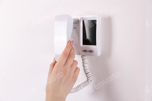 Preview: Woman answering intercom call at home, closeup
