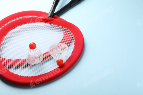 Preview: Badminton rackets and shuttlecocks on light blue background, closeup. Space for text