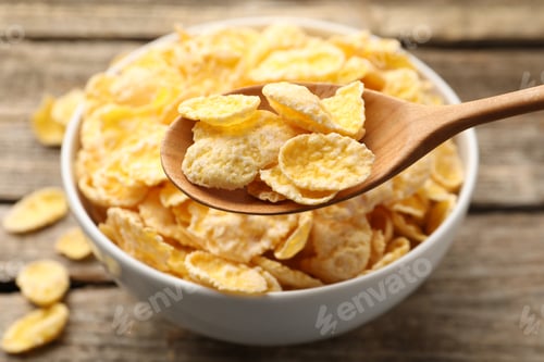 Preview: Eating tasty corn flakes with spoon at wooden table, closeup