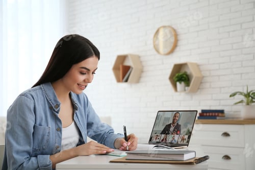 Preview: Woman having video chat with her coworkers via laptop at home