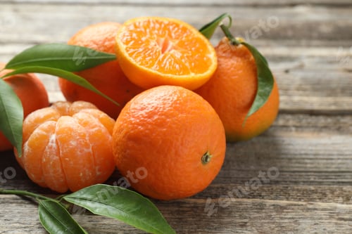 Preview: Fresh tangerines and green leaves on wooden table, closeup. Space for text