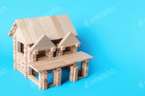 Preview: House made of wooden blocks on light blue background. Space for text