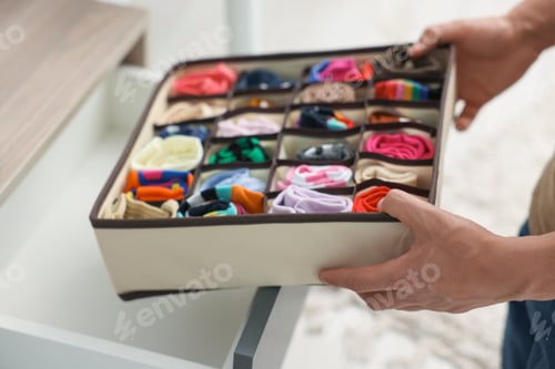 Preview: Man putting organizer with socks into drawer indoors, closeup