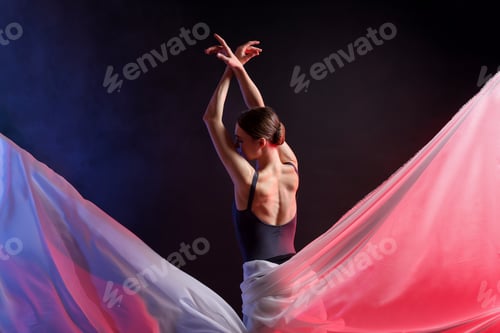 Preview: Graceful ballerina with white veil practicing dance moves in color lights against black background