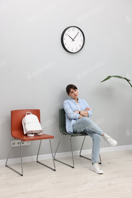 Preview: Woman sitting on chair and waiting for appointment indoors