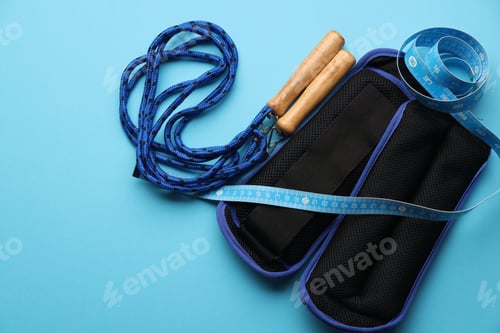 Preview: Measuring tape, jumping rope and ankle weights on light blue background, flat lay