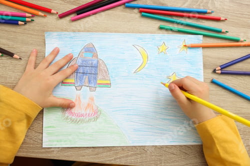 Preview: Little boy drawing with pencil at wooden table, top view