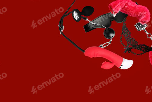 Preview: Sex toys and accessories falling on red background. Space for text