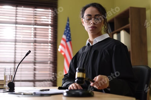 Preview: Judge striking gavel at wooden desk indoors