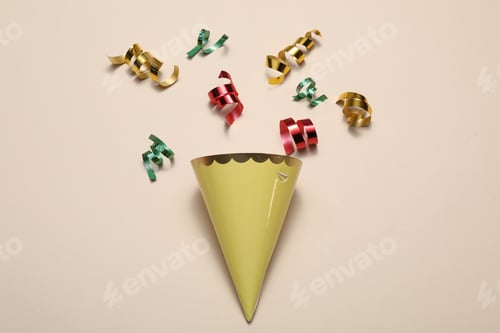 Preview: Shiny party streamers and cone on beige background, flat lay