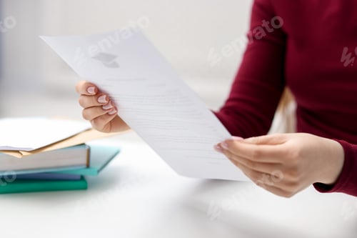 Preview: Woman with letter from university at white table indoors, closeup