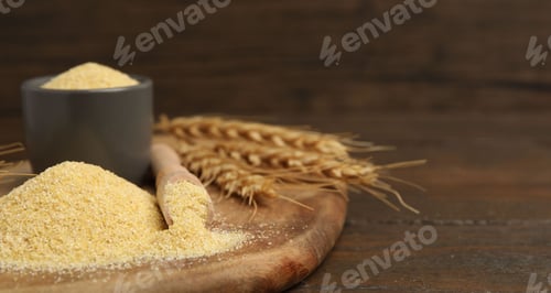 Preview: Raw semolina and spikes on wooden table, closeup. Space for text