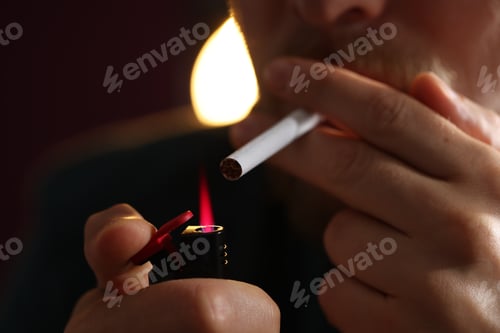 Preview: Man lightning cigarette on blurred dark background, closeup