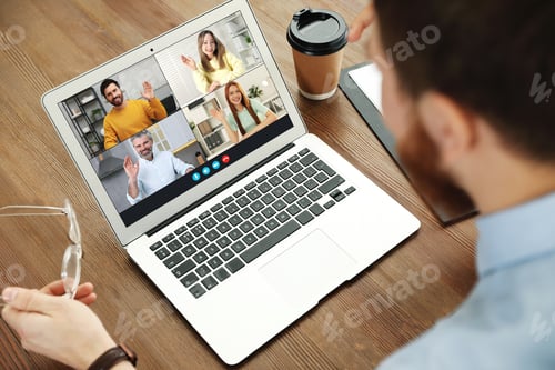 Preview: Man having video chat with his coworkers via laptop at home, closeup