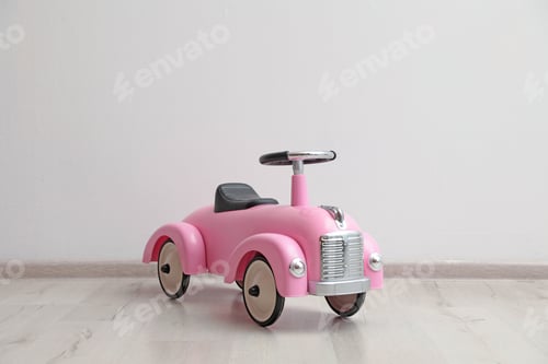 Preview: Pink toy car near white wall indoors