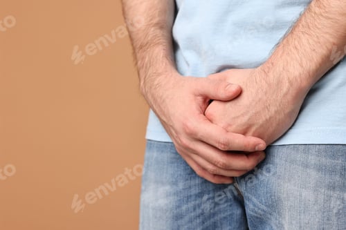 Preview: Urology. Man suffering from pain on beige background, closeup. Space for text