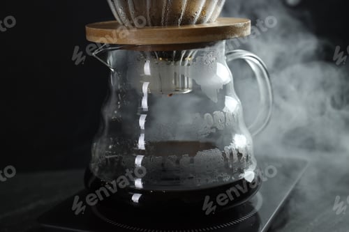 Preview: Glass chemex coffeemaker with tasty drip coffee on black table, closeup