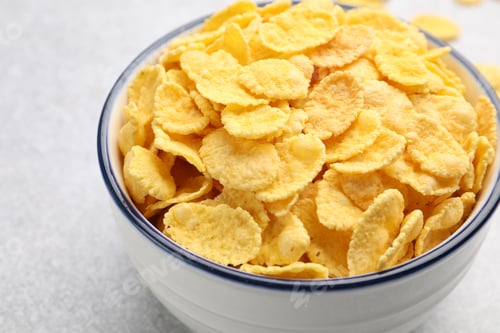 Preview: Tasty corn flakes in bowl on light grey background, closeup