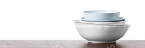 Preview: Stack of clean bowls on wooden table against white background